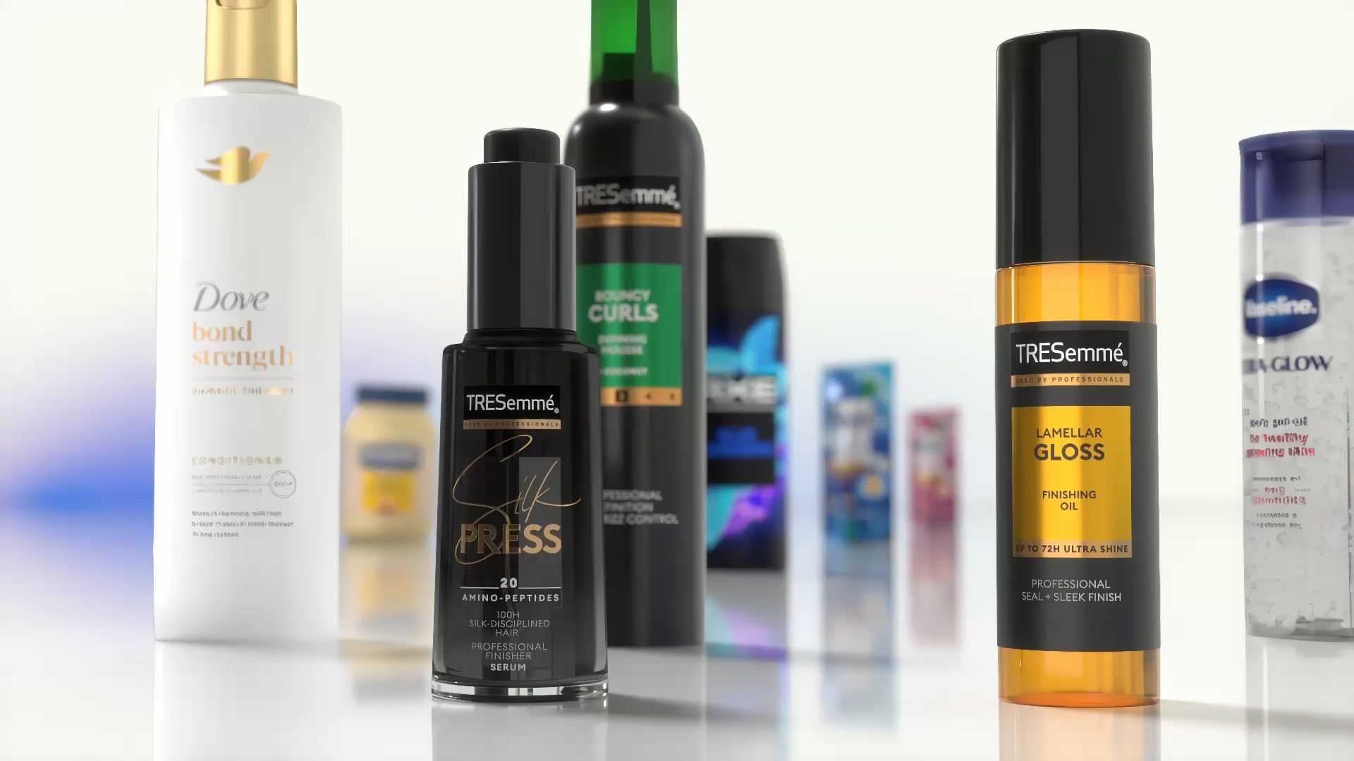 Prim-plan cu diverse produse de îngrijire a părului și corpului expuse pe o suprafață reflectorizantă. Printre produsele vizibile se numără balsamul Dove Bond Strength, serul TRESemmé Silk Press, uleiul de finisare TRESemmé Lamellar Gloss și alte produse Unilever în fundal.